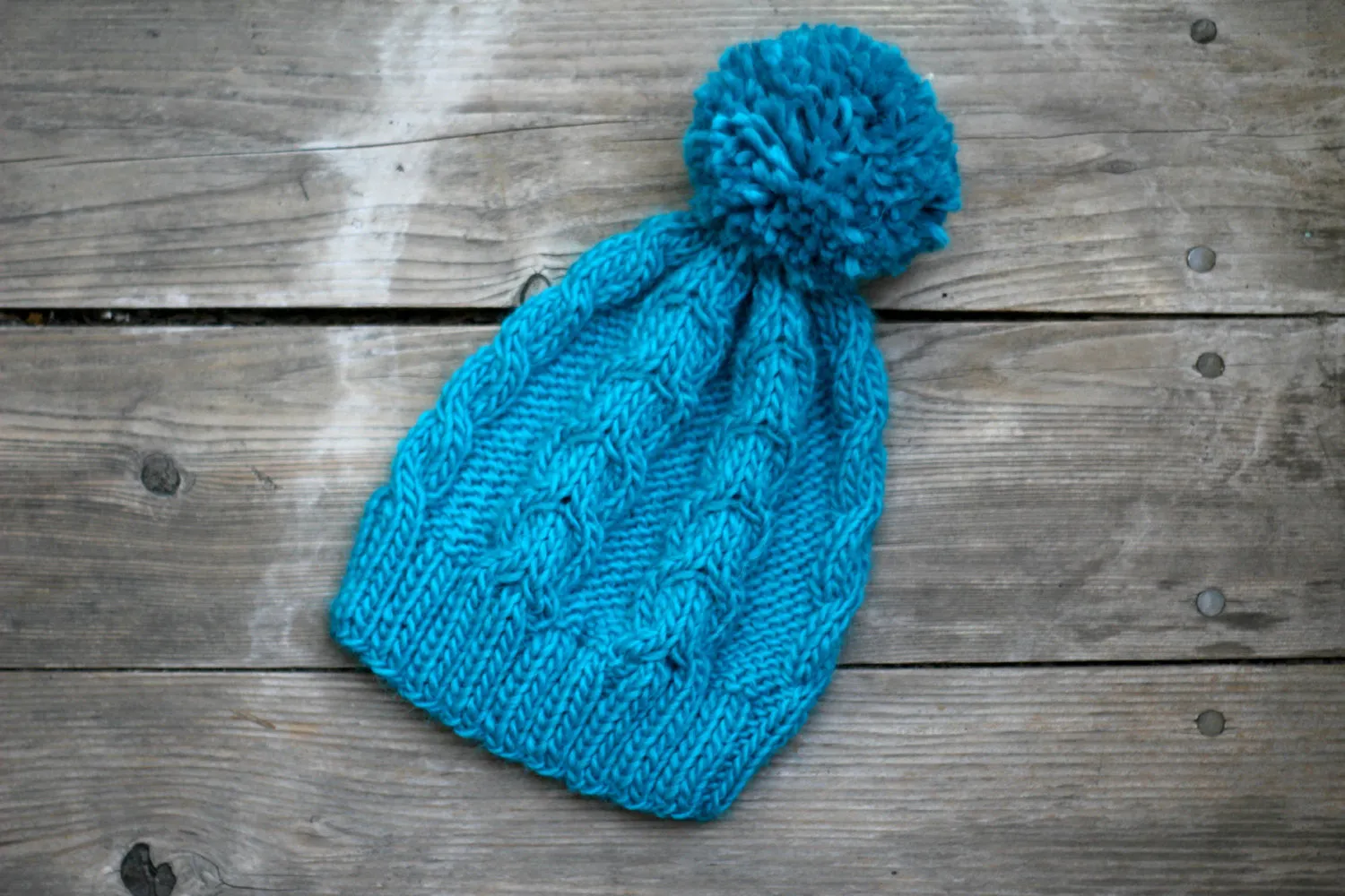 Knit beanie hat in turquoise blue color with cables and pom pom