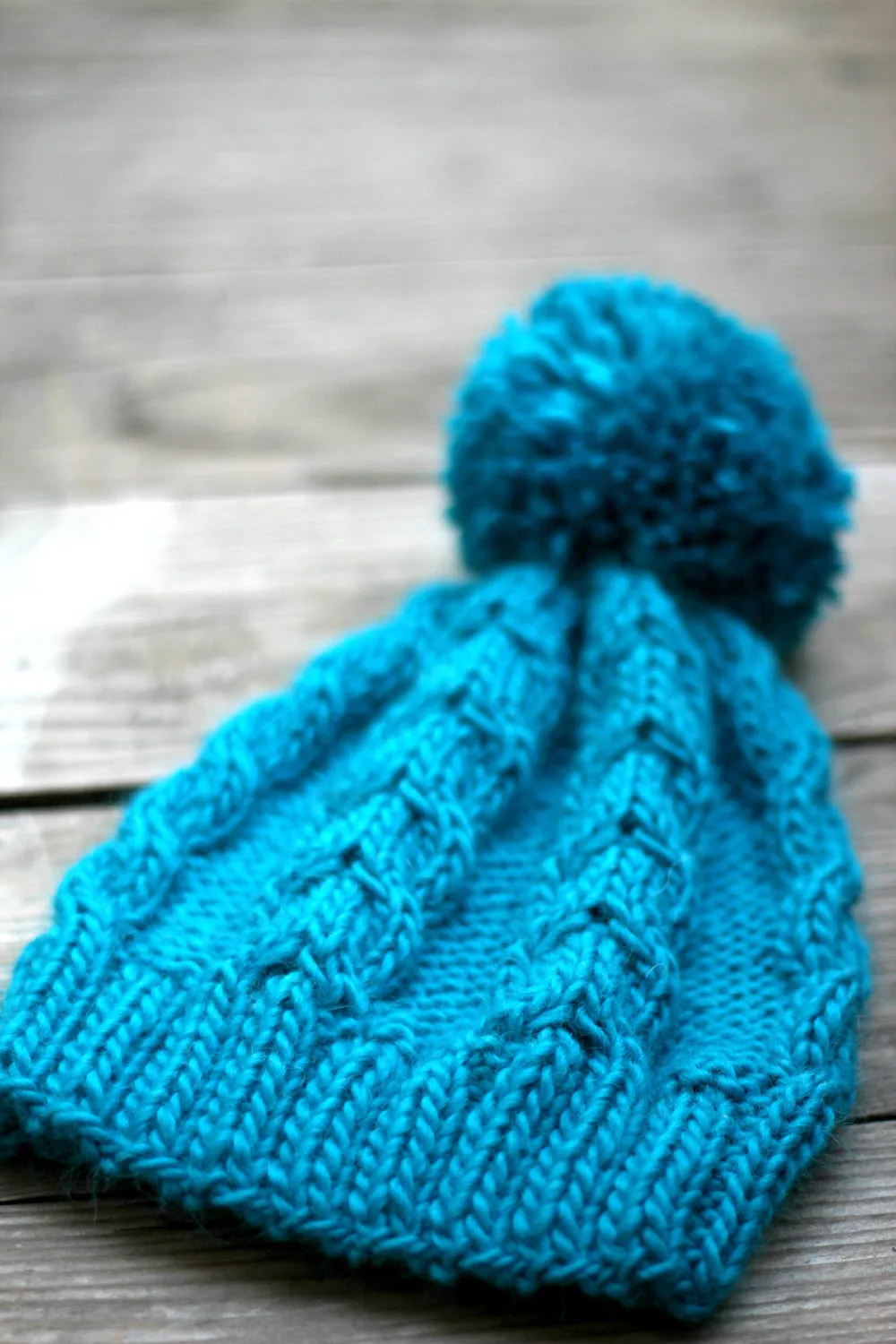 Knit beanie hat in turquoise blue color with cables and pom pom