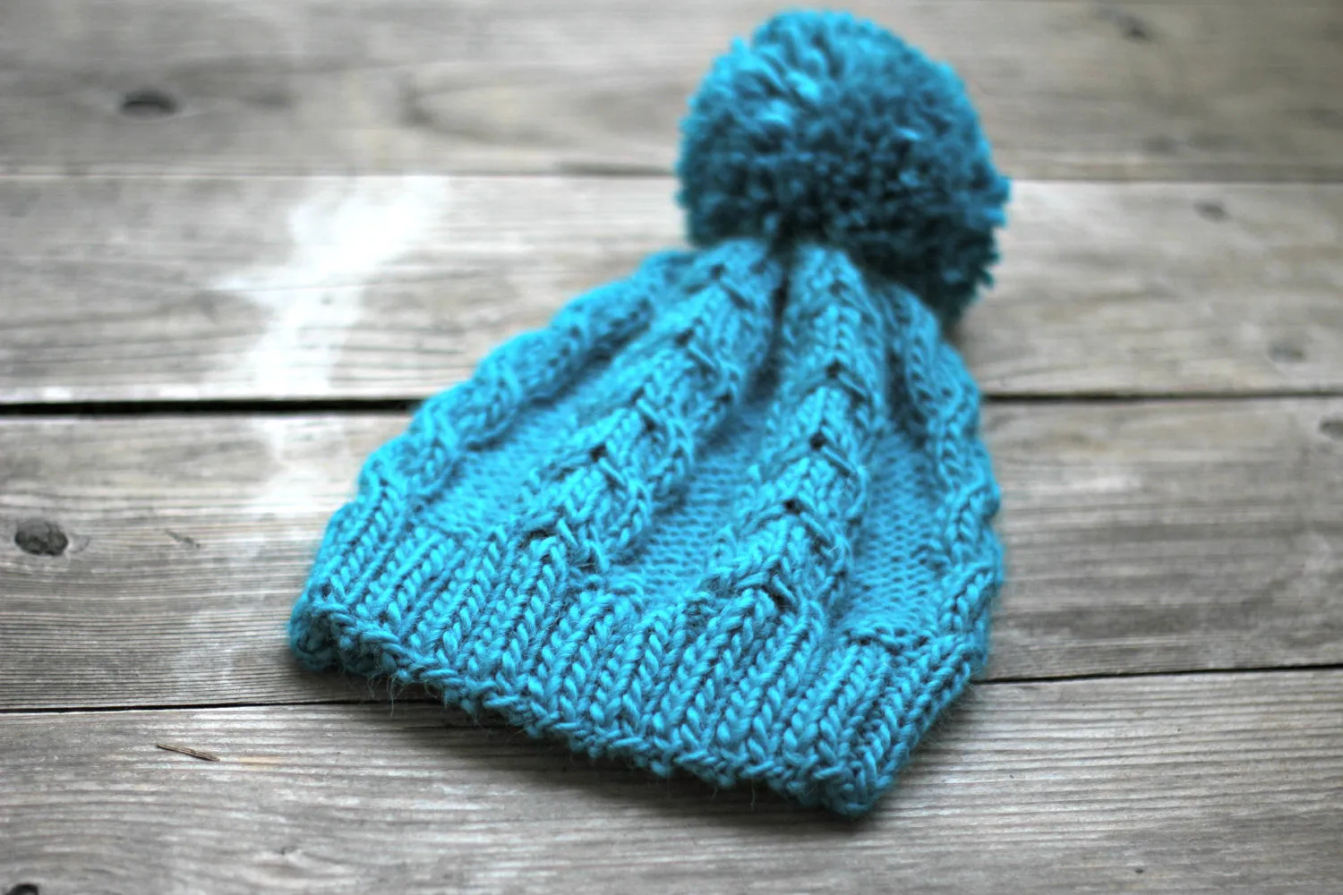 Knit beanie hat in turquoise blue color with cables and pom pom