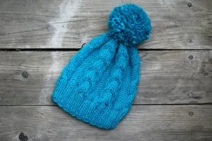 Knit beanie hat in turquoise blue color with cables and pom pom